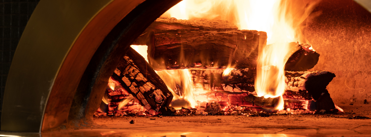 A pizza oven with wood in it and its burning